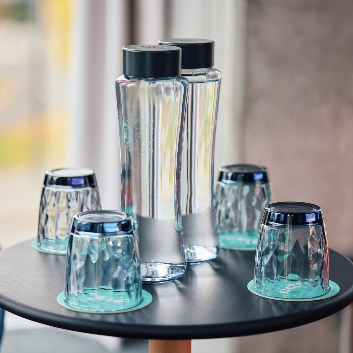 BRITA Twist-flessen met zwarte doppen, staande op een ronde zwarte tafel.