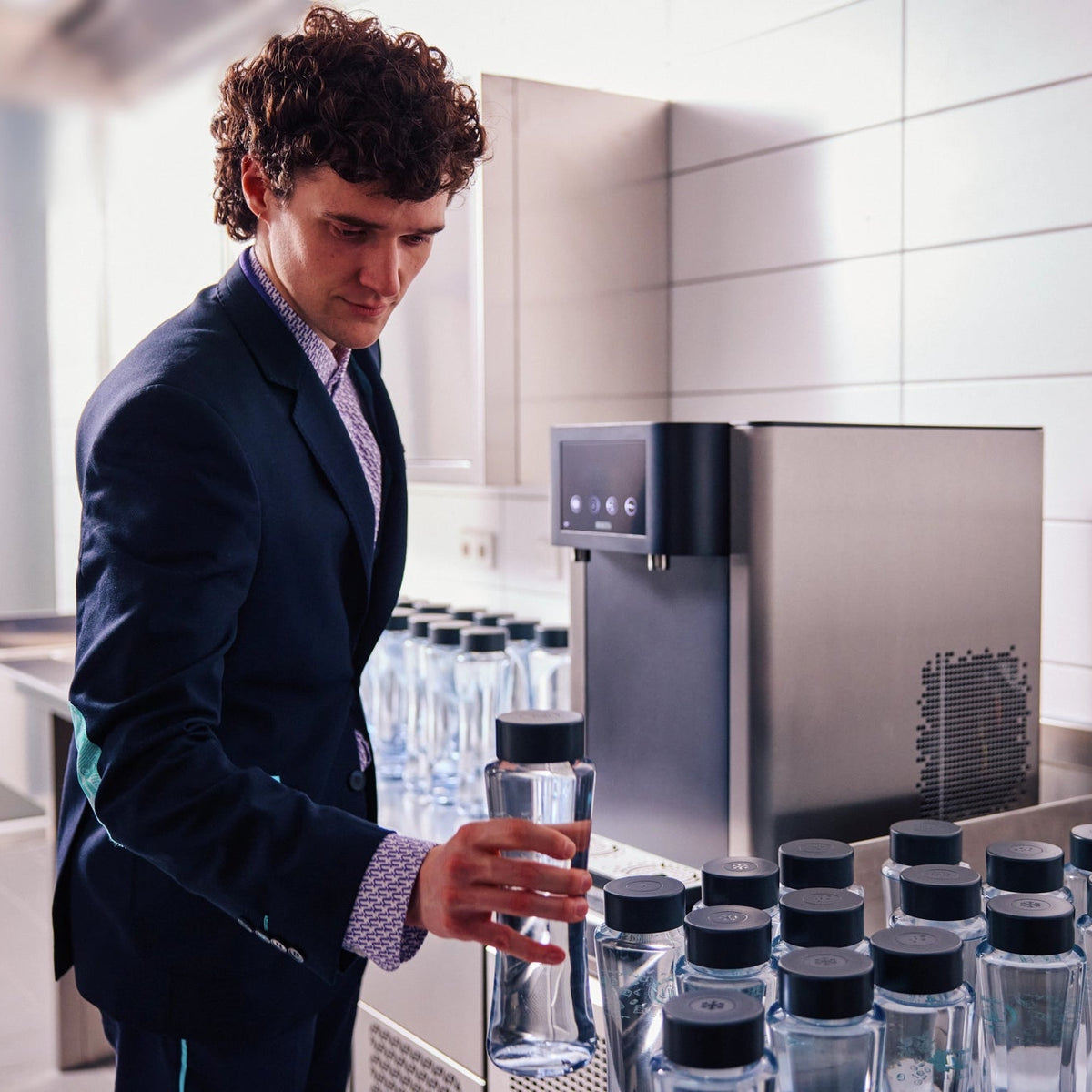 Een man in pak die voor een BRITA Fill Pro-waterdispenser staat met meerdere Twist-flessen.