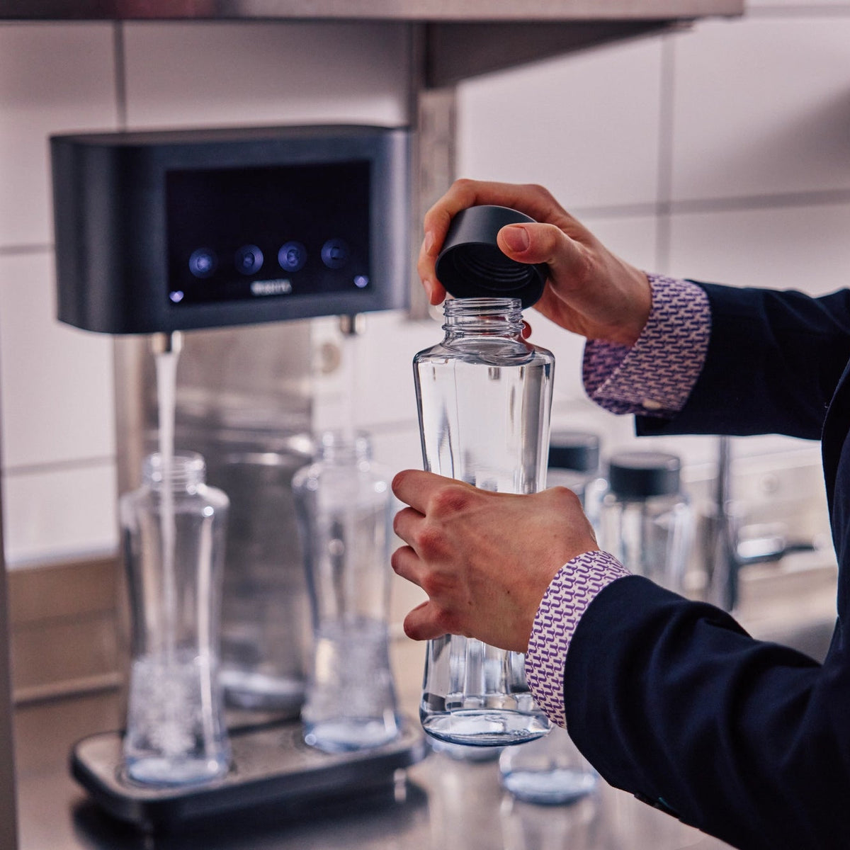 Iemand die een BRITA Twist-fles met een donkere dop vasthoudt voor een BRITA Fill T-Tap.
